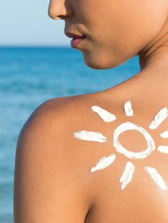 Woman applying sunscreen outdoors by the water